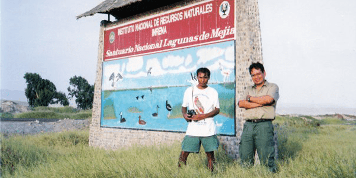 A la entrada de Lagunas de Mejía Ernesto, en pie, junto al cartel que anuncia el Santuario Nacional Lagunas de Mejia